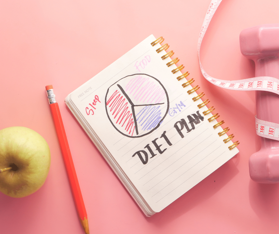 Pink background with a journal that says "diet plan" alongside a pencil and apple