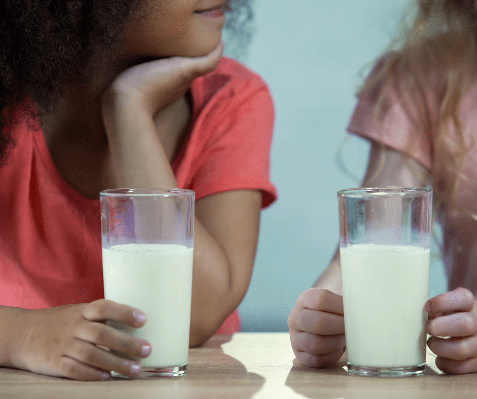 two kids holding a glass of milk