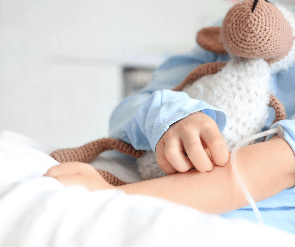 a kid's hand in the hospital holding a stuffed animal