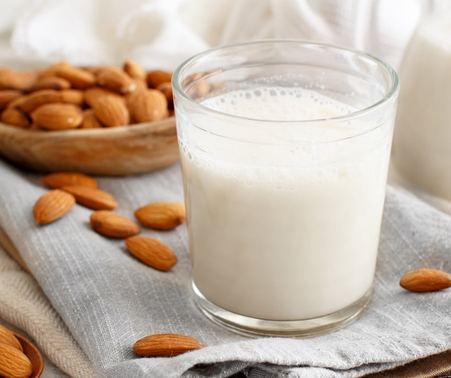 a white glass of milk surrounded by almonds, lowering the risk of prostate cancer